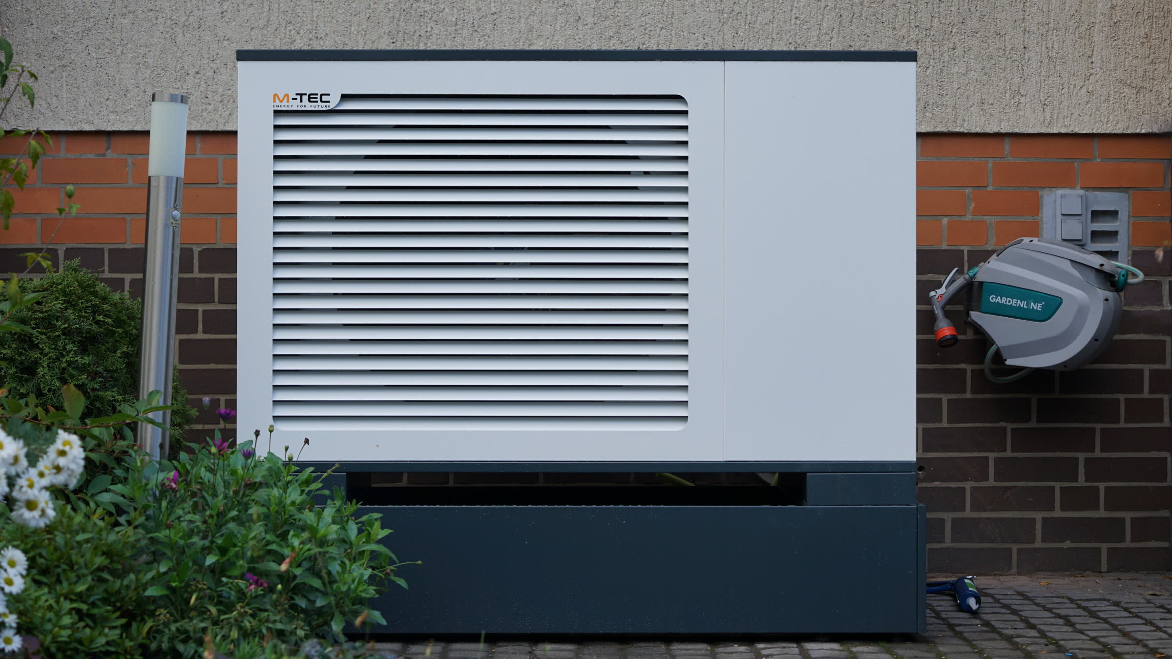 Von uns montierte M-TEC Wärmepumpen-Außeneinheit vor einer Klinkerwand